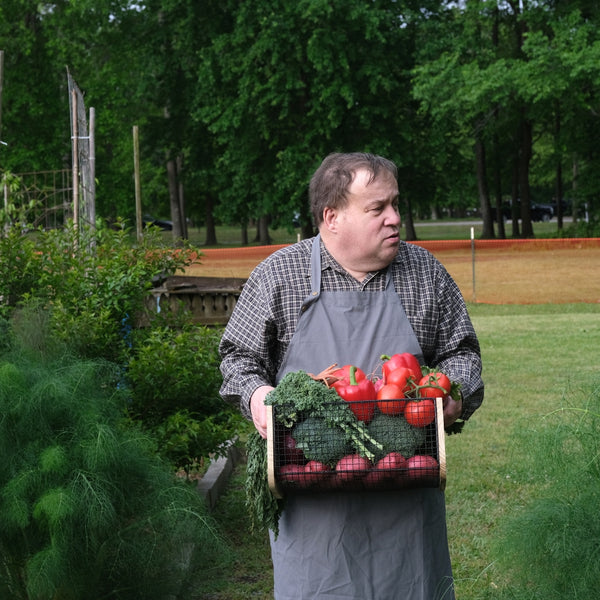 Man in a garden holding a basket of vegetables